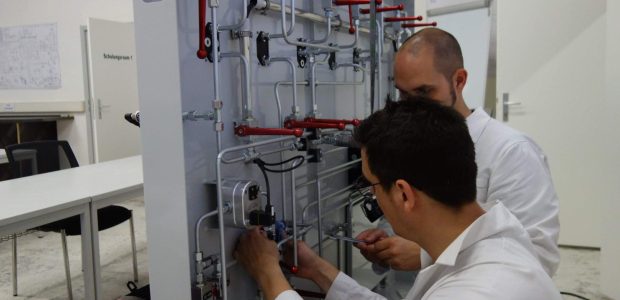 Instandhaltung von Mobilhydraulik in Salzbergwerken - Mitarbeiter in weißen Anzügen schrauben an Hydraulikleitungen